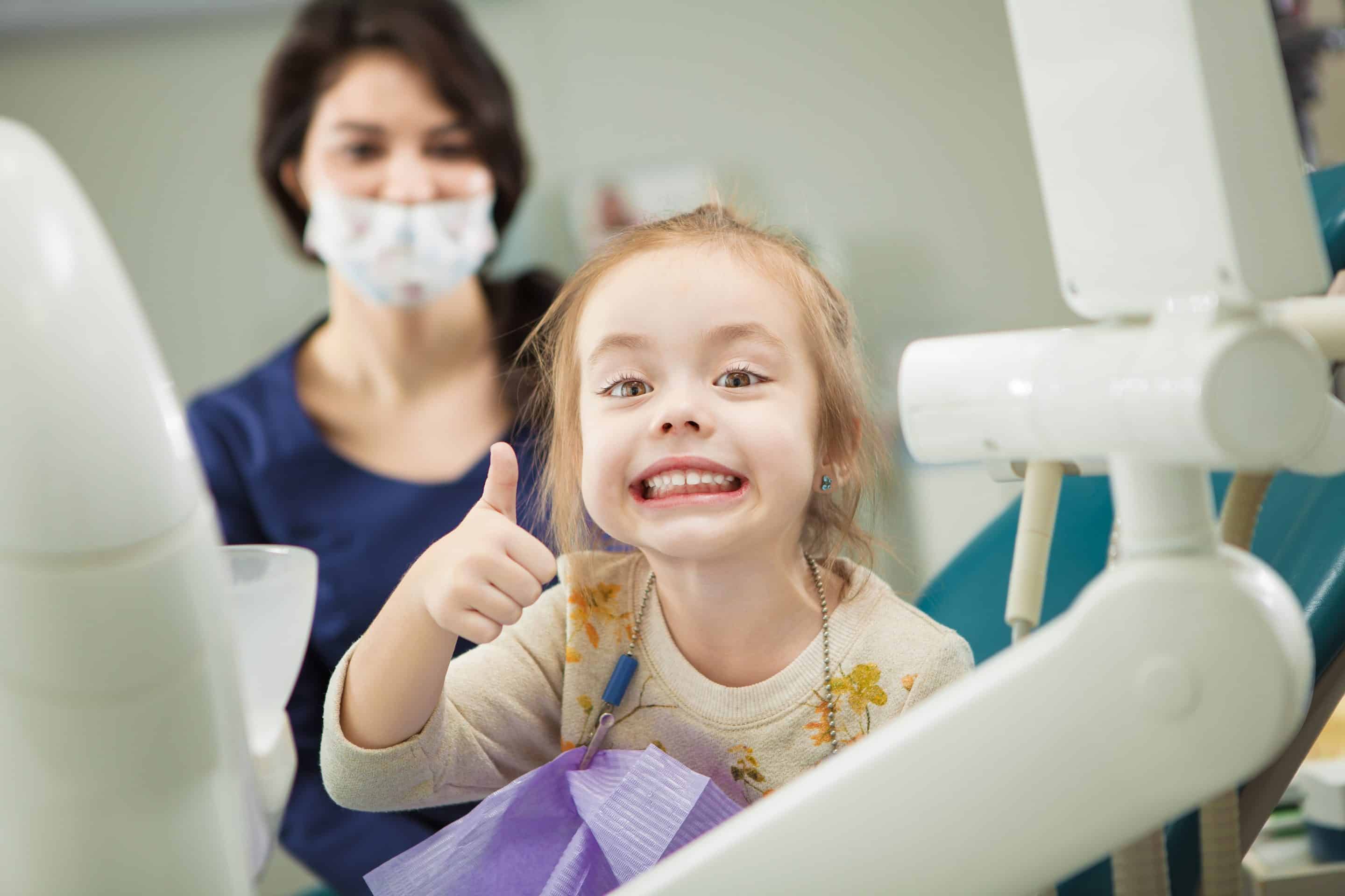 Girl giving a thumbs up with a happy smile at the dentist in Lexena and Lawrence KS